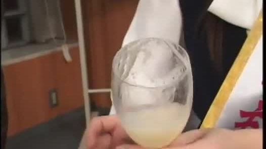 Playful asian drinks cum from a glass